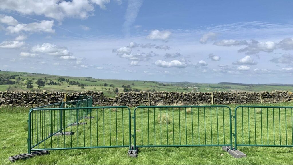 Green metal fencing in place around grass.