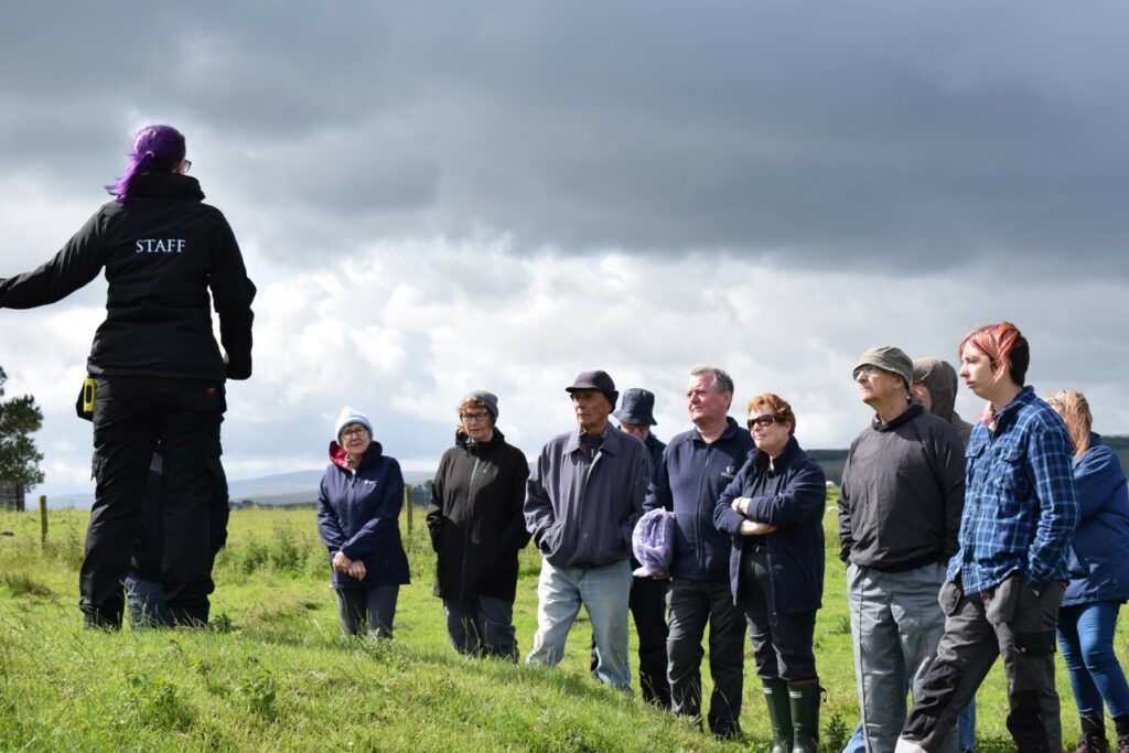 Senior archaeologist Rachel Frame and a group of volunteers standing in a field.