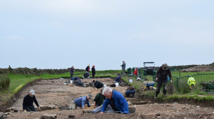 Group of people excavating at archaeological site in a field