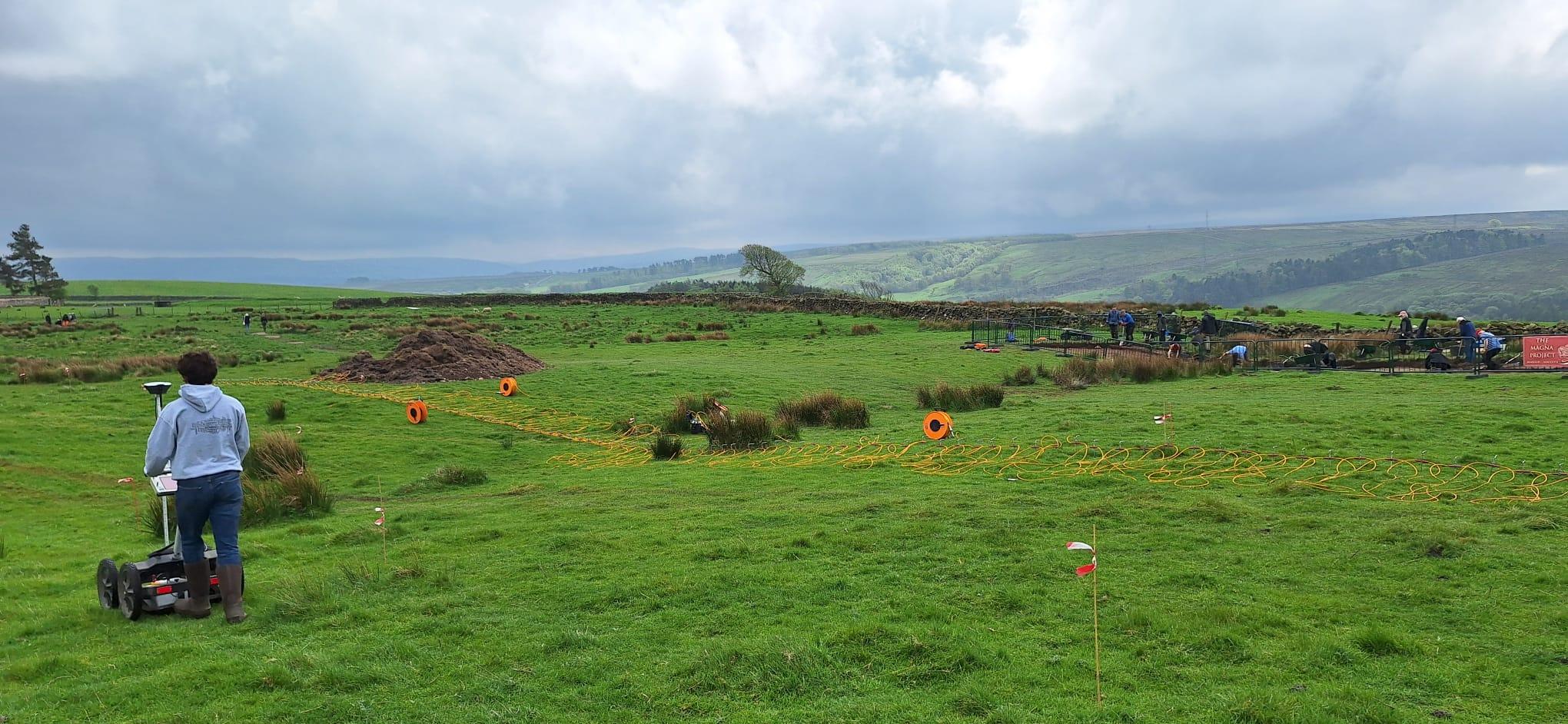 Conducting GPR (foreground) and ERT (middle ground) surveys of the Vallum at Magna, with the ongoing excavations in the background.