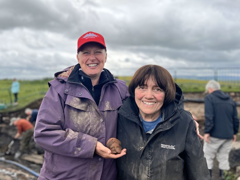 Two women holding a small terracotta head.