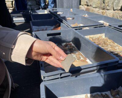 A hand holding a fragment of ancient Roman pottery