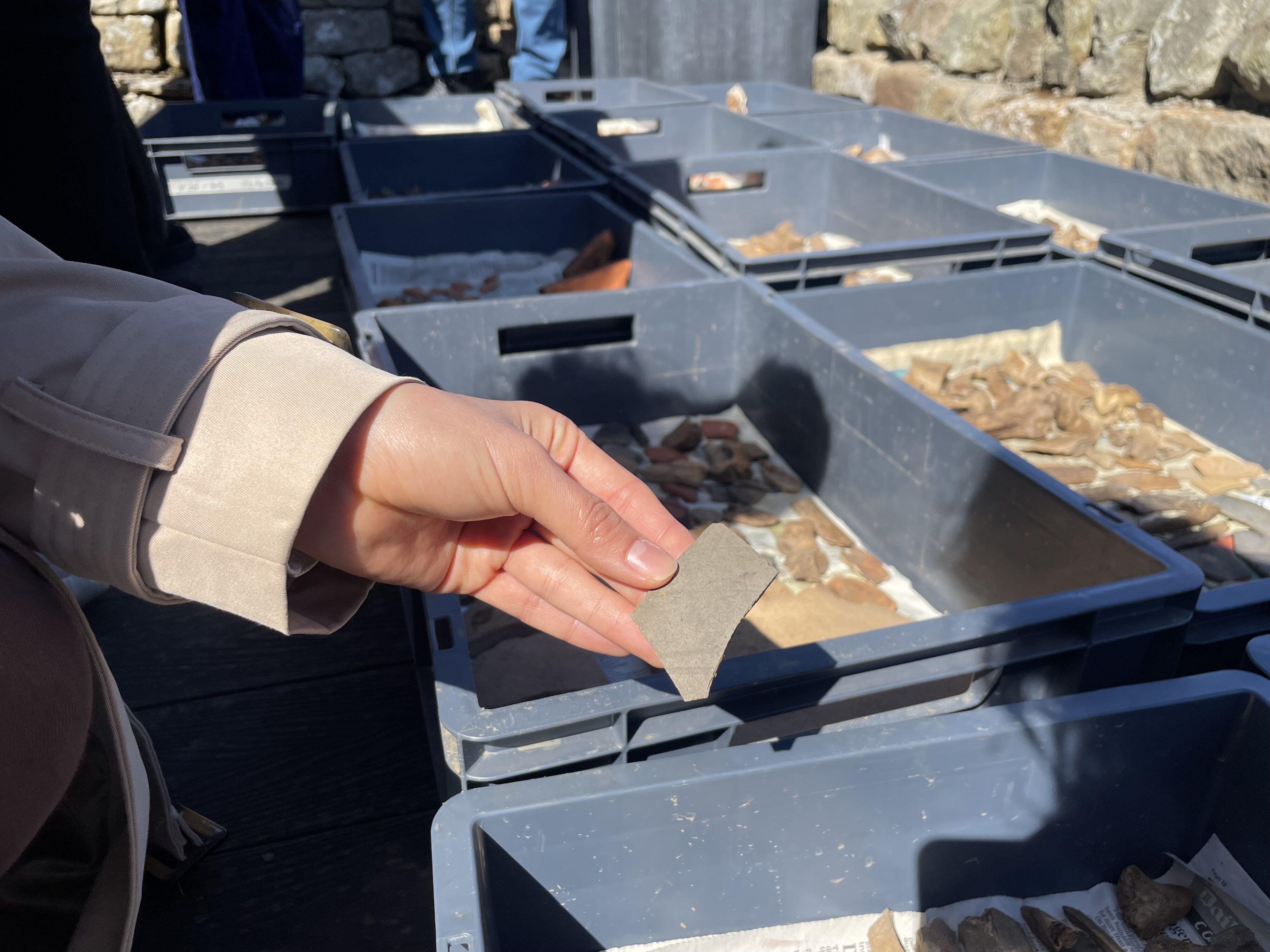 A hand holding a fragment of ancient Roman pottery