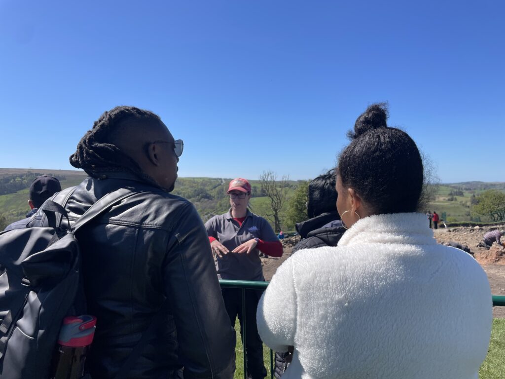 Group of people visiting the Magna excavations and talking to an archaeologist.